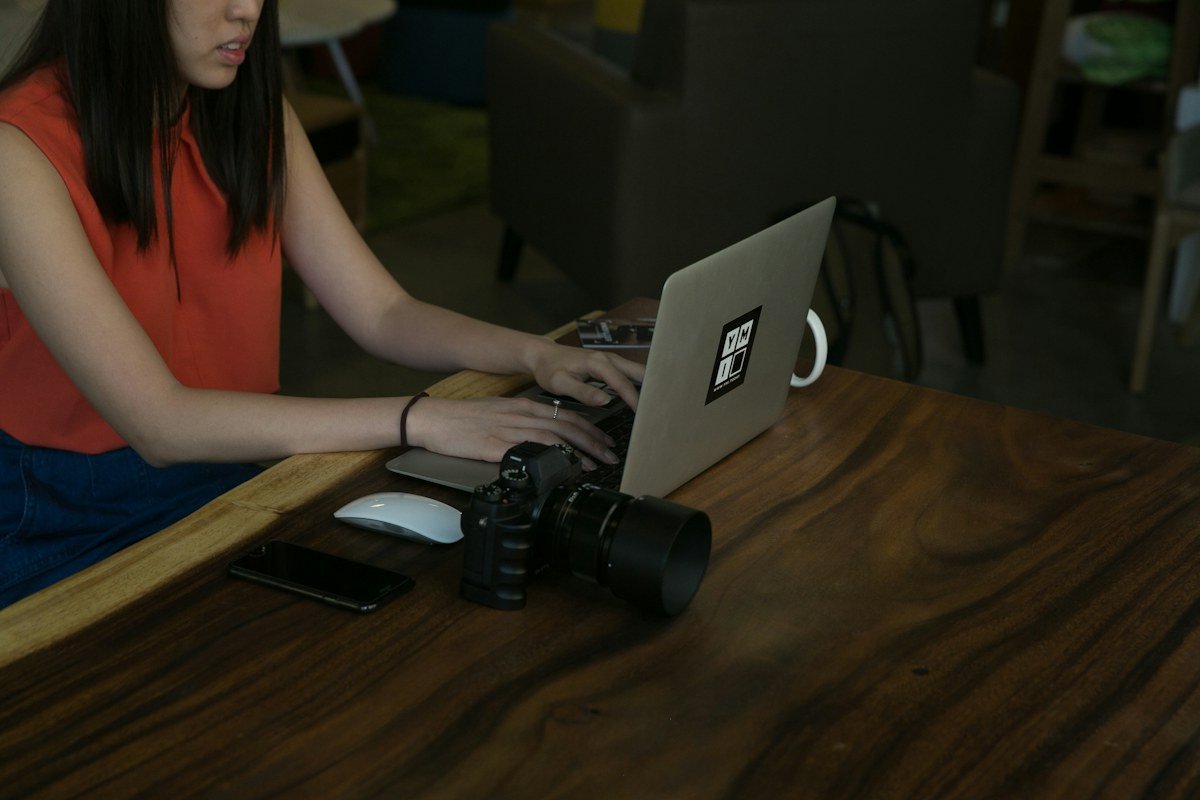 A creative professional using a laptop with camera equipment nearby