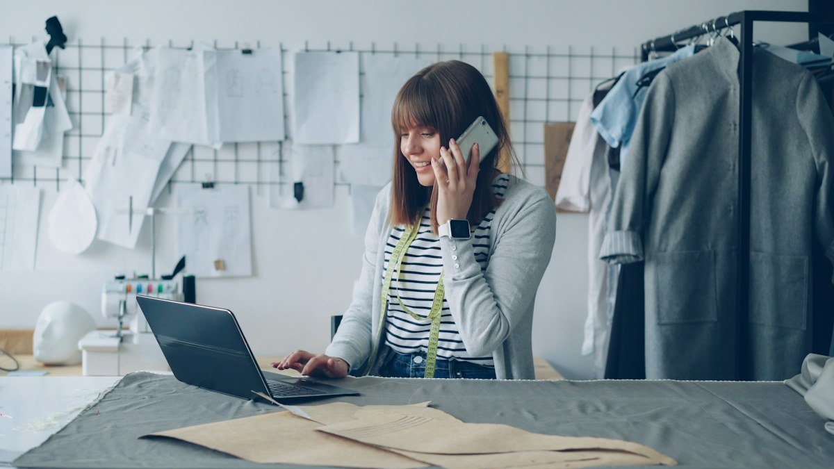 A small business owner speaking on the phone while using her laptop