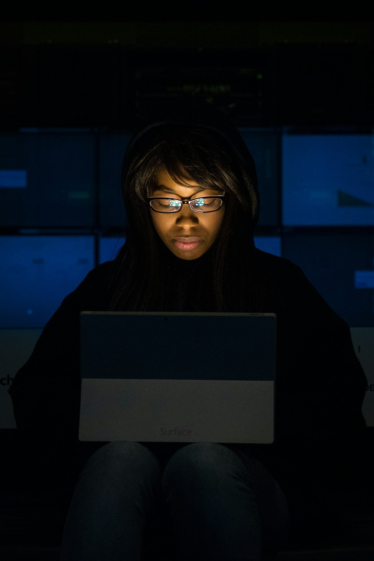 A woman reviewing work on her laptop in a low-lit office