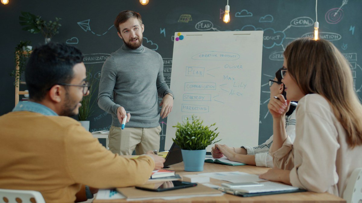 Colleagues discussing a plan beside a whiteboard