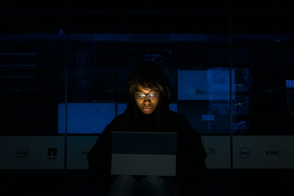 A woman concentrating on her laptop in a dark workspace
